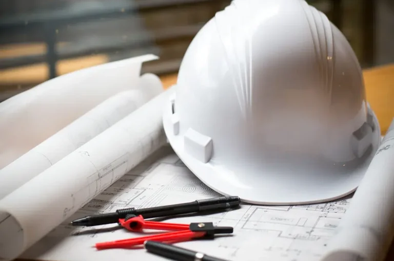 Casque de chantier posé sur des plans d'architecture