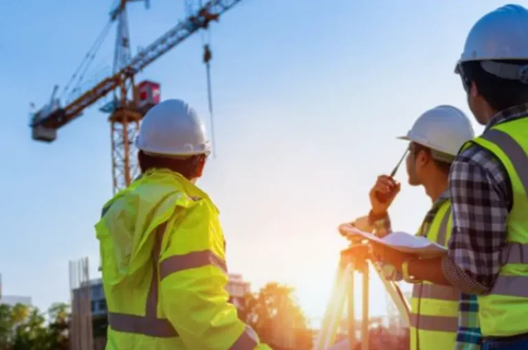 Équipe de chantier avec casques de sécurité devant une grue